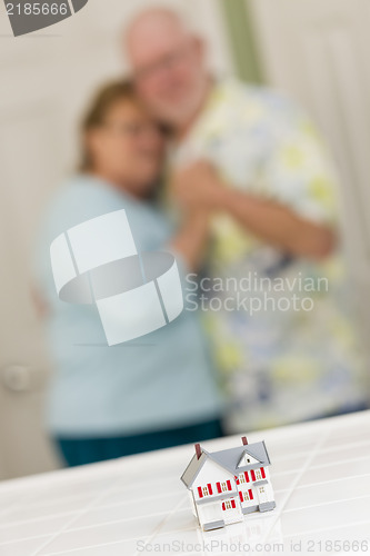 Image of Senior Adult Couple Gazing Over Small Model Home on Counter