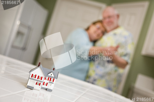 Image of Senior Adult Couple Gazing Over Small Model Home on Counter