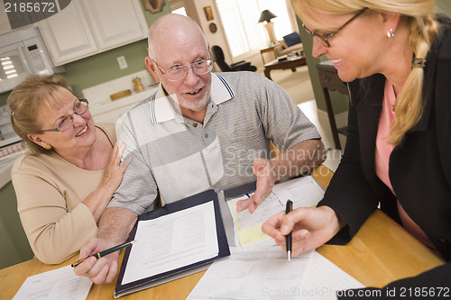 Image of Senior Adult Couple Going Over Papers in Their Home with Agent