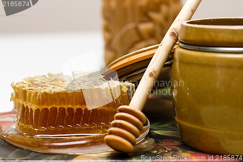 Image of Honey in pot, honeycomb and stick