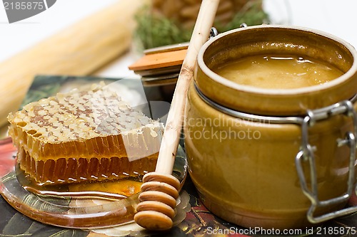 Image of Honey in pot, honeycomb and stick