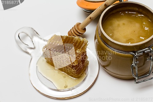 Image of Honey in pot, honeycomb and stick