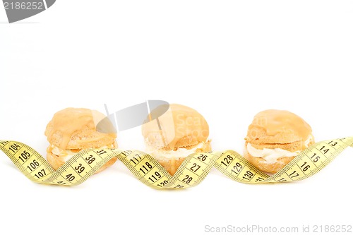 Image of concept of slimming, caramel cakes with measuring tape