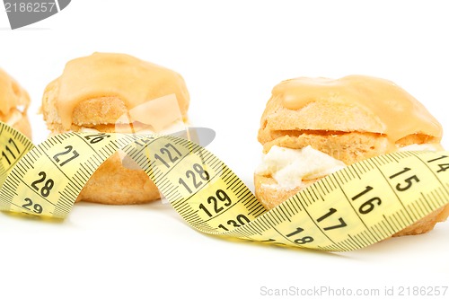 Image of concept of slimming, caramel cakes with measuring tape