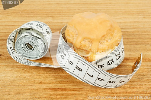 Image of concept of slimming, caramel cake with measuring tape