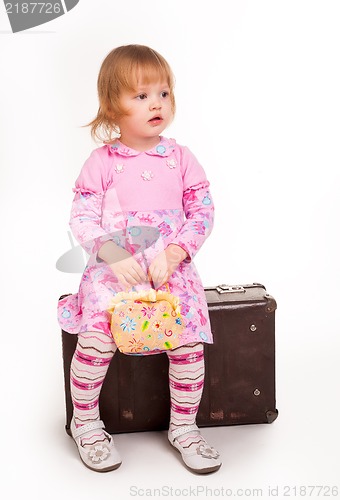 Image of portrait of adorable young girl on old suitcase