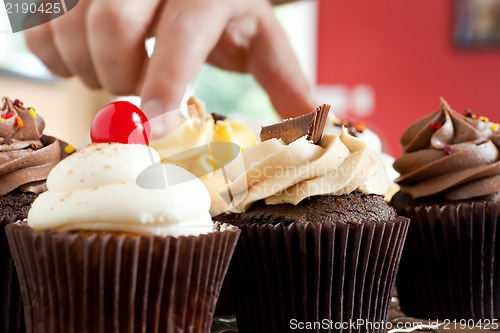 Image of Hand Grabbing a Gourmet Cupcake