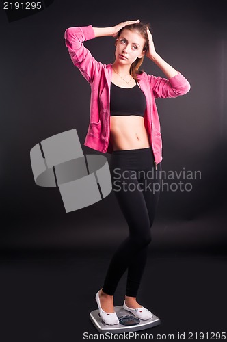Image of happy young woman on weight scales