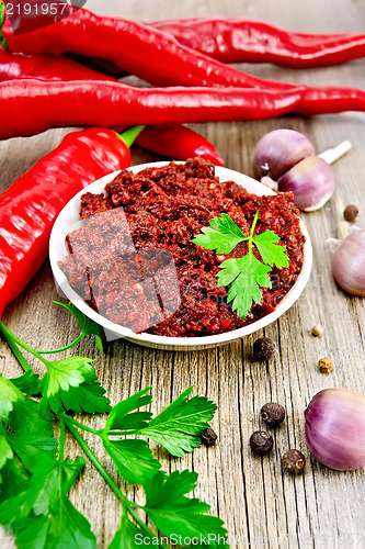 Image of Adjika with fresh hot peppers on the old board