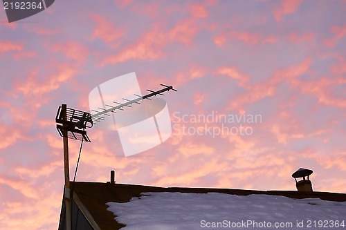 Image of TV antenna against reddish cloudy sky