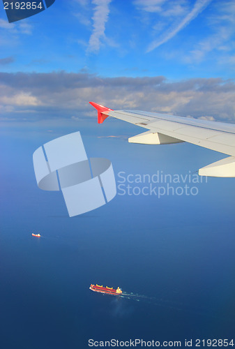 Image of cargo ships under wing of flying plane