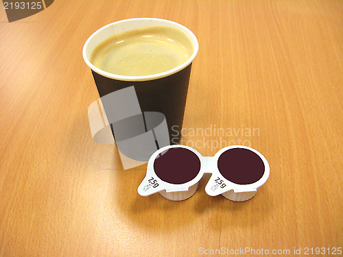 Image of paper glass of coffee and two portion of cream
