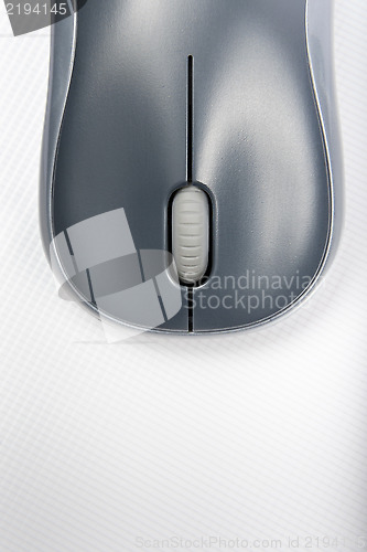 Image of A wireless mouse positioned vertically on the cover of a laptop