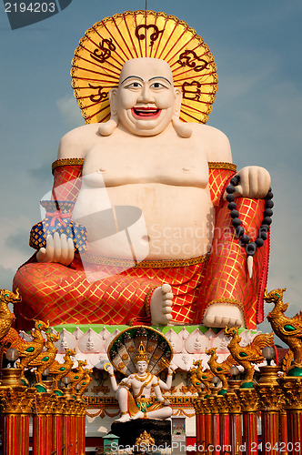 Image of Fat laughing Buddha over blue sky