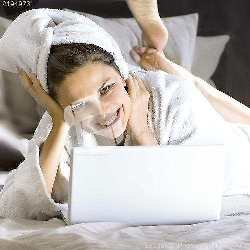 Image of happy woman on the bed with laptop