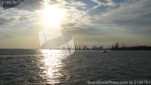 Image of everning sea with hoisting crane in the seaport