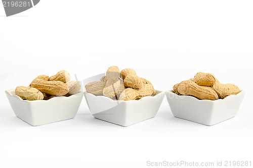 Image of Three white bowls filled with peanuts on a white background