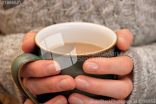 Image of Two hands keeping warm, holding a hot cup of tea or coffee