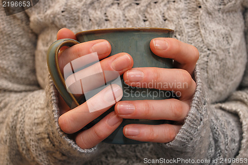 Image of Two hands holding a mug of drink