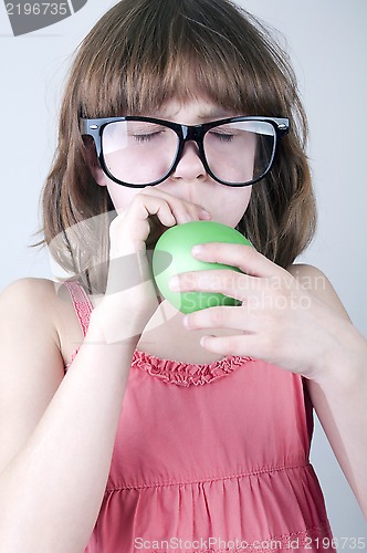 Image of funny  girl with herd sunglasses blowing a balloon