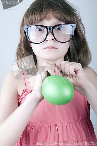 Image of funny  girl with herd sunglasses blowing a balloon