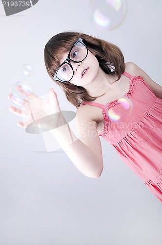 Image of child with nerd glasses plaing with soap bubbles