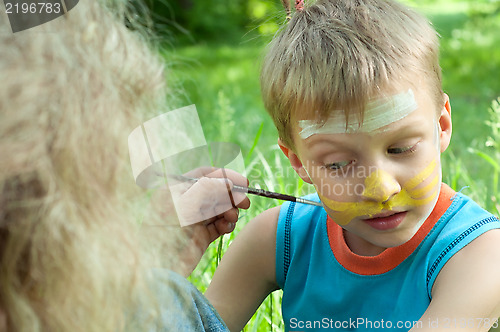 Image of portrait of a child with his face being painted