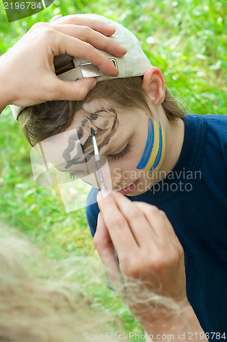 Image of portrait of a child with his face being painted