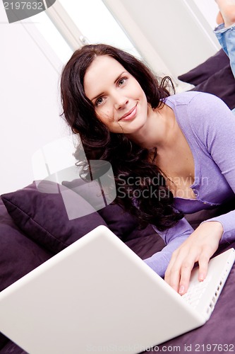 Image of smiling woman on couch with notebook