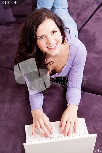 Image of smiling woman on couch with notebook