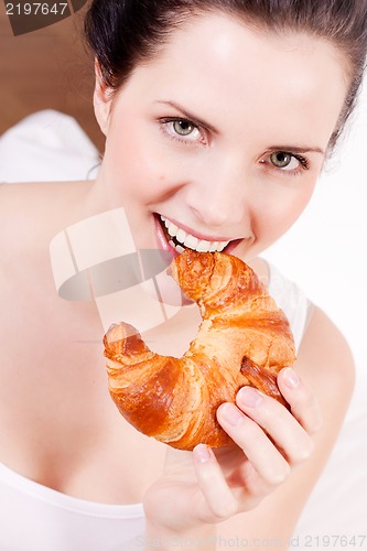 Image of smiling woman eating a croissant