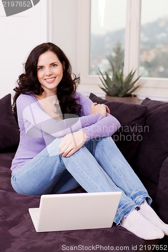 Image of smiling woman on couch with notebook