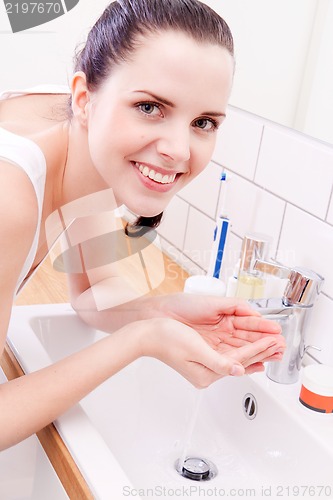 Image of woman washing her face in bathroom