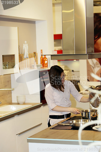 Image of Young housewife cooking in a kitchen