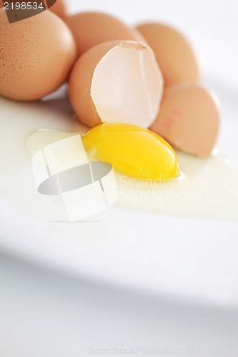 Image of One broken egg in the foreground on a plate