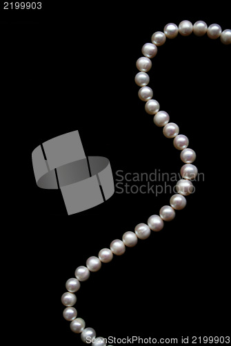 Image of White pearls on the black silk as background 