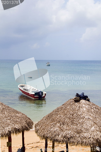 Image of beach thatch roof restaurant huts with fishing boat Caribbean Se