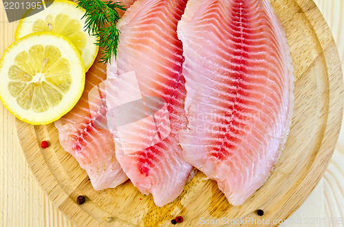 Image of Fillets tilapia with lemon on a round board