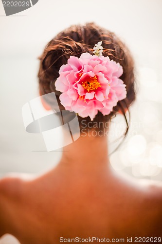 Image of brunette woman with pinkroses in hair, vertical orientation