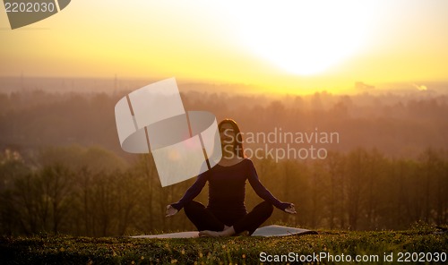 Image of Beautiful young woman meditating on a patch of grass