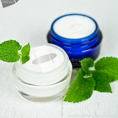 Image of face cream in jars with urtica leaves