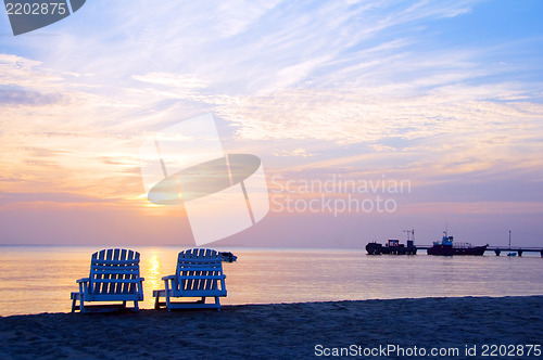 Image of sunset on Picnic Center beach  lounge chairs and boats in distan