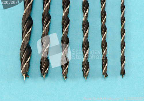 Image of different size wood drill bits for wood on blue 