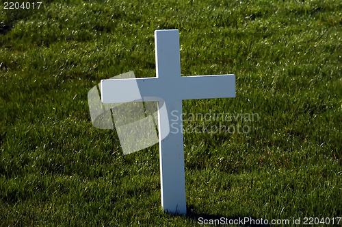 Image of A lone marble cross at a cemetery