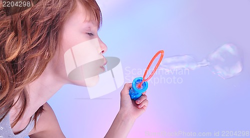 Image of  girl  blowing soap bubbles against bright background