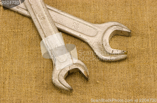 Image of pair screw spanners wrench tools crossed on linen 