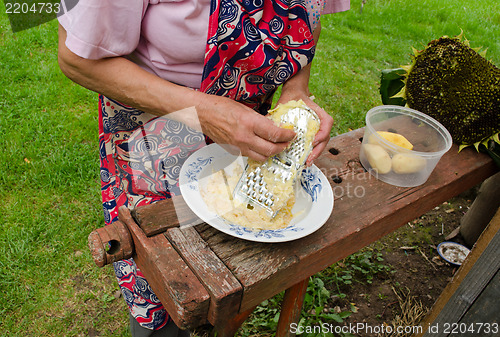 Image of senior woman grate peel potatoes steel shredder 