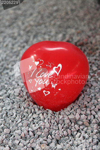 Image of Red shaped heart with writing sitting on pebbles