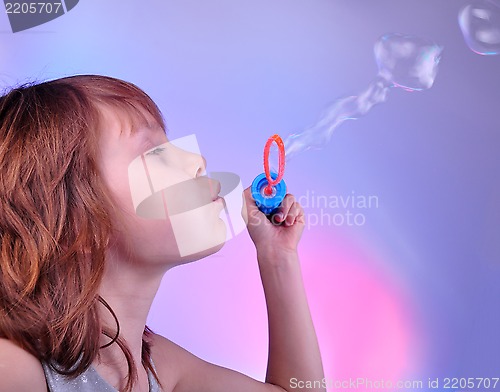 Image of little girl blowing soap bubbles in bright surrounding