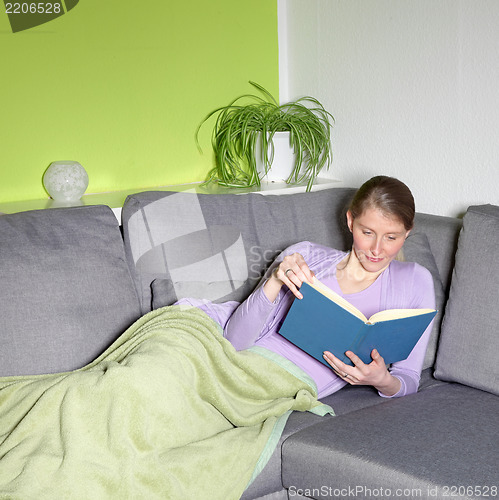 Image of Woman relaxing reading on a sofa